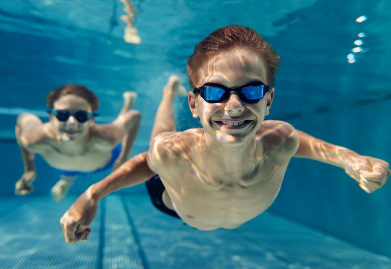Potápějící se chlapci v bazénu.