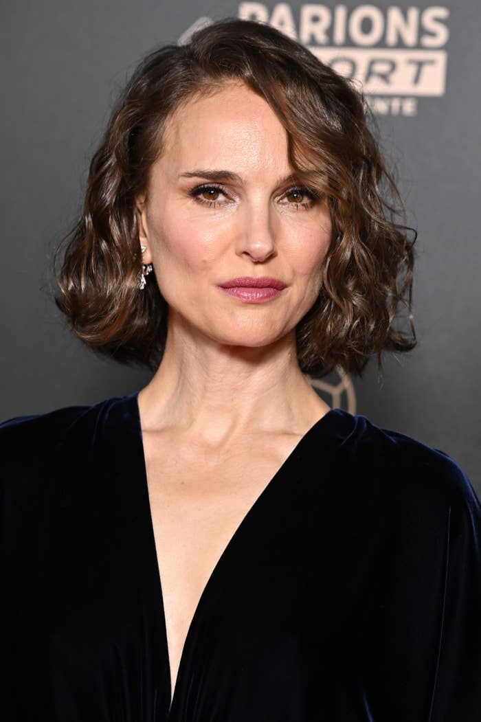Osoba s vlnitým bob účesem nosící elegantní tmavý V-krk outfit na akci