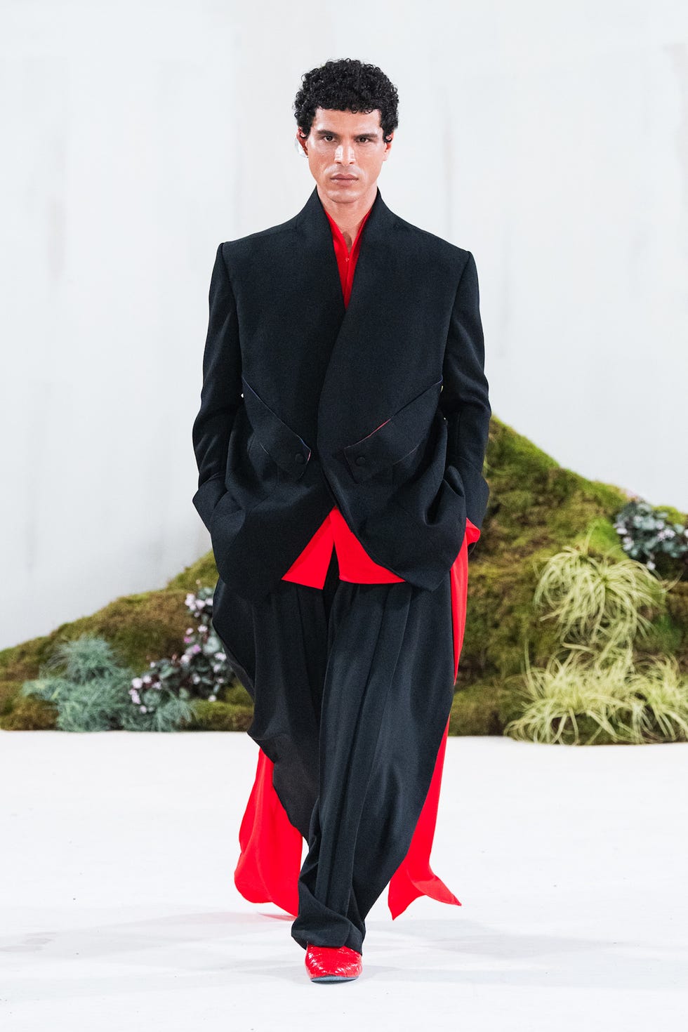 Model na přehlídkovém molu v černém a červeném outfitu
